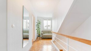 Un couloir doté d’un plancher en bois, d’une plante en pot, d’un banc et d’un escalier avec une rampe en bois.