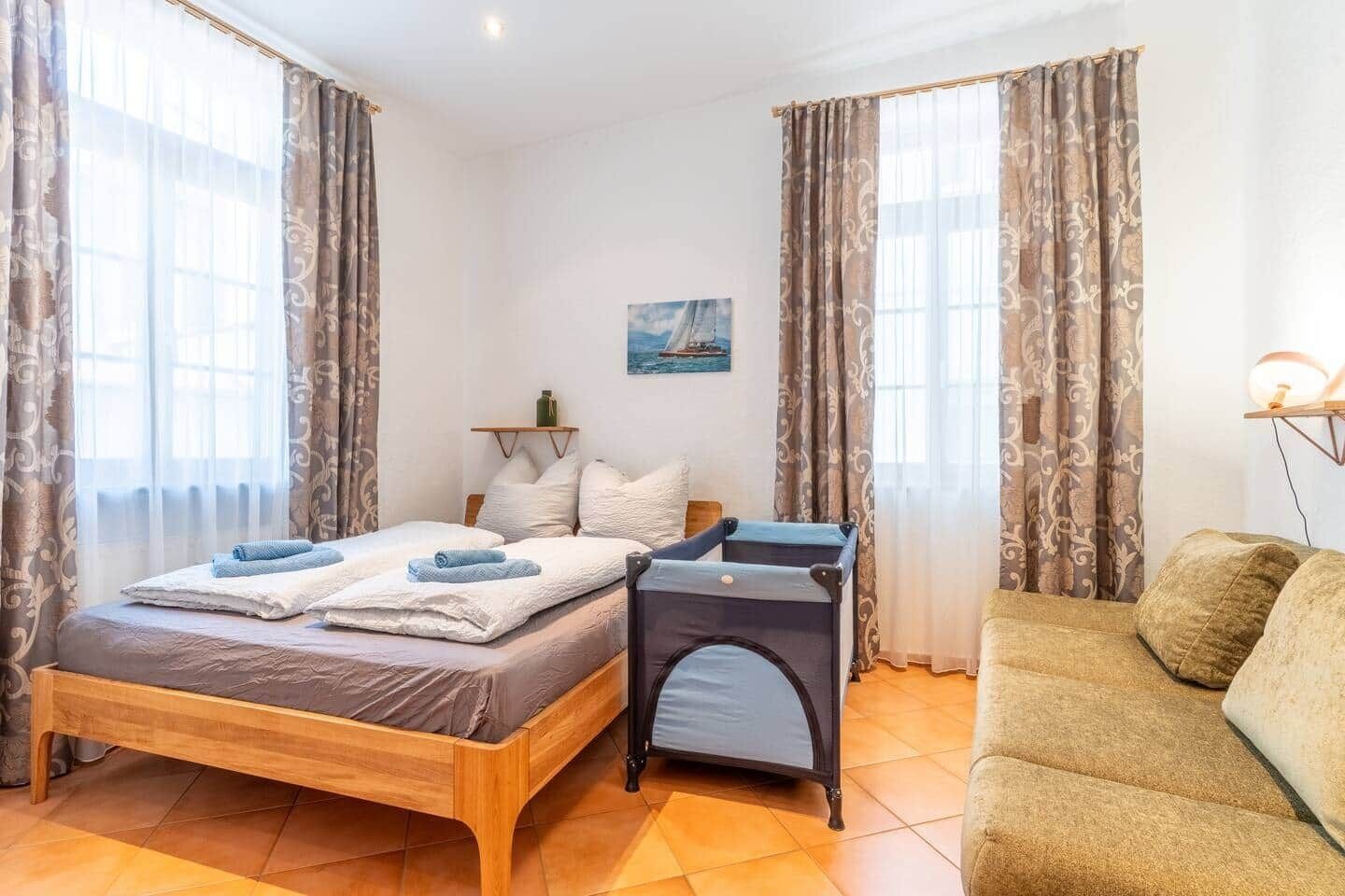 Ein Schlafzimmer mit einem hölzernen Bett, einem Nachttisch, einer Couch und einem Gemälde an der Wand.