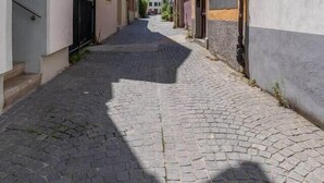 Uma rua de paralelepípedos estreita, ladeada por edifícios com varandas e janelas.