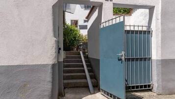 A narrow alleyway with a blue gate, cobblestone pavement, and a staircase leading to a building.