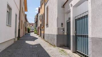 Una estrecha calle adoquinada flanqueada por edificios con balcones y una entrada porticada.