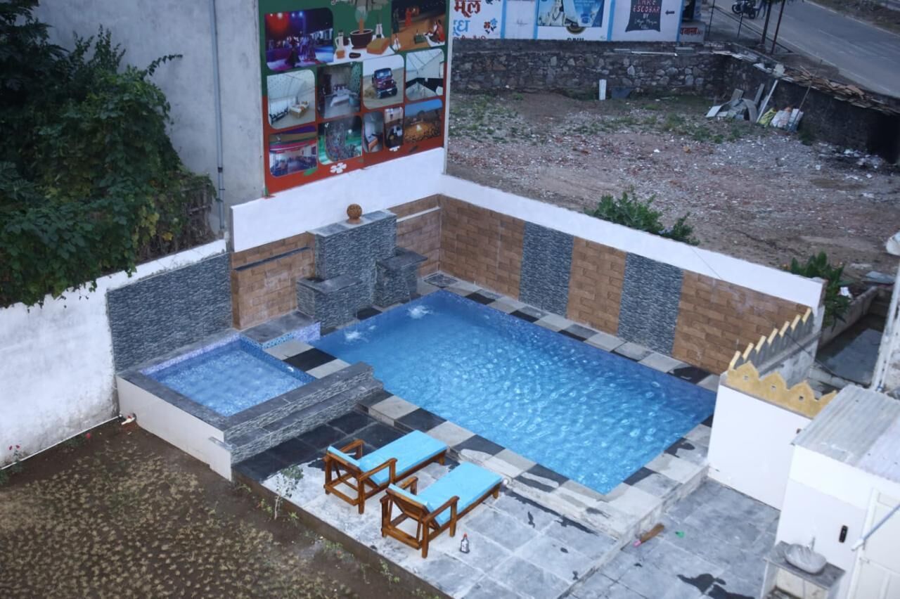 A swimming pool with a tiled deck, a few lounge chairs, and a stone wall.