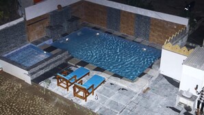 A swimming pool with a tiled deck, a hot tub, and lounge chairs. - Hotel L S Restaurant & Spa (Udaipur)