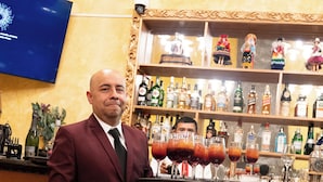 A man in a suit standing in front of a bar area with a variety of bottles and glasses. - AYNI BOUTIQUE HOTEL  (Cusco)
