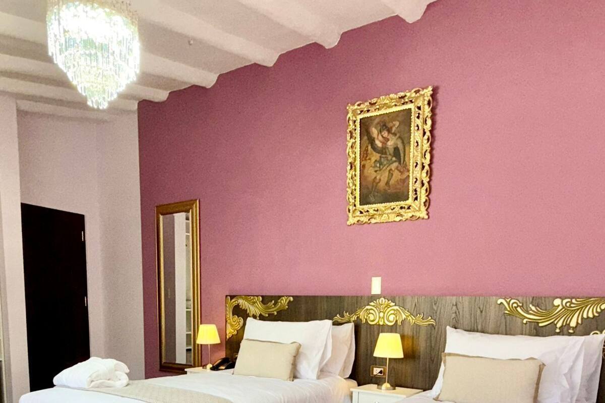 Ein Hotelzimmer mit zwei Betten, einer Kristallleuchter, einem Spiegel und einem gerahmten Bild an der Wand.
