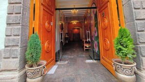A hallway with two large wooden doors, a chandelier, and potted plants. - AYNI BOUTIQUE HOTEL  (Cusco)