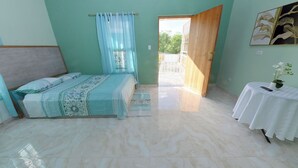 A bedroom with a bed, a table with a vase, and a door leading outside. - Spacious 5-bedroom villa in charming Santo Domingo with AC and Pool (Santo Domingo)