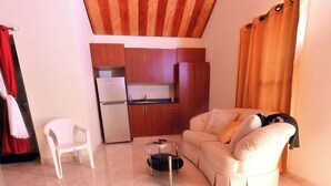 A compact living space with a sofa, a small table, a refrigerator, and a kitchenette. - Spacious 5-bedroom villa in charming Santo Domingo with AC and Pool (Santo Domingo)