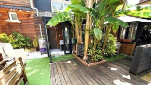 A wooden deck with artificial grass, a brick planter with plants, and a wooden fence. - Résidence Hôtelière de l Estuaire (Le Havre)