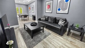 Een moderne woonkamer met een bank, salontafel en een televisie op een meubel.