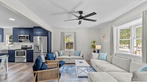 A modern kitchen with dark blue cabinets, stainless steel appliances, and a white ceiling fan. - 4 min to beach, fully fenced yard + games, pet and kid friendly! (Oak Island)