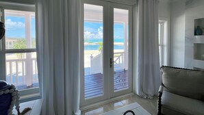 Une pièce avec vue sur la plage, un canapé blanc et une terrasse en bois.