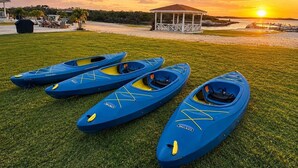 Une zone herbeuse où sont alignés quatre kayaks bleus.