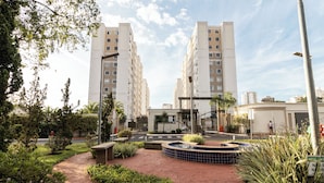 A residential area with two tall apartment buildings, a landscaped garden with a circular water feature, and a pedestrian pathway.