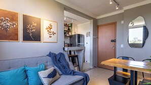 A modern living room with a grey sofa, teal cushions, and a wooden dining table.