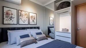 A bedroom with a bed, a nightstand, a wardrobe, and two framed floral artworks on the wall.