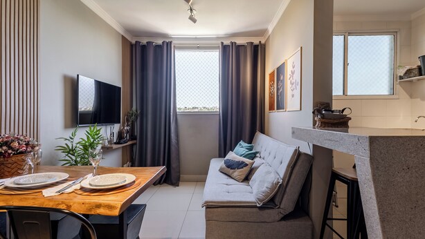 A modern living room with a sofa, dining table, TV, and kitchen area.