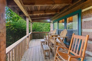 Una terraza de madera con barandilla, sillas y una mesa.