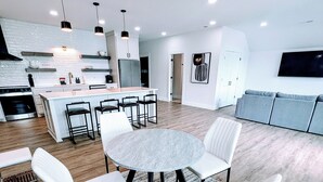 A modern kitchen with white cabinetry, a central island, and bar stools.