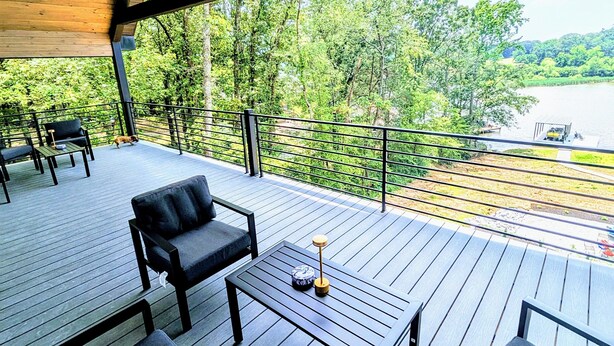 A wooden deck with outdoor seating and a view of a lake.