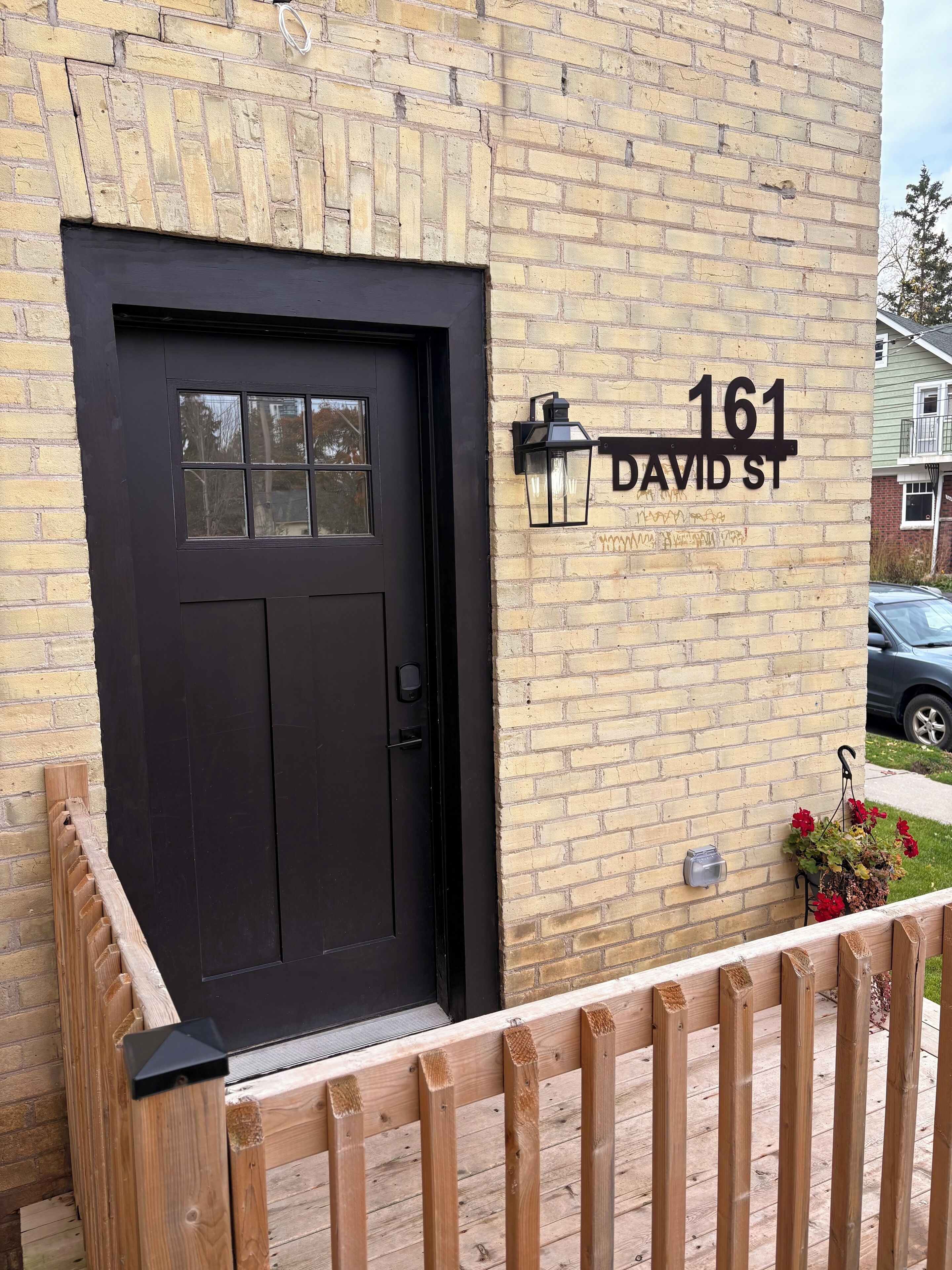 A black door with a window, a mailbox, and a street sign reading "161 DAVID ST."