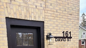 Una puerta negra con un ventanal, un buzón y una señal de calle que dice "161 DAVID ST".