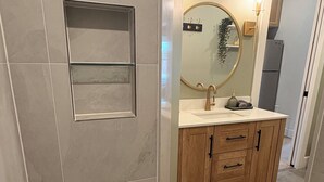 Un baño de diseño moderno, con un espejo grande, un lavamanos y armarios de madera.