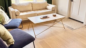 Una sala de estar moderna con un sofá color beige, un sillón azul y una mesa de centro blanca.