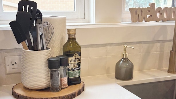 Una encimera de cocina con cubierta de mármol blanco, armarios de madera debajo y una ventana con persianas.