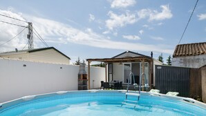 Ein Schwimmbad mit Fliesen, einer überdachten Terrasse und Blick zum Himmel.