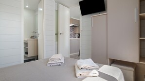 Ein Hotelzimmer mit Bett, Fernseher, Schrank und einem durchgegangene Tür sichtbaren Badezimmer.