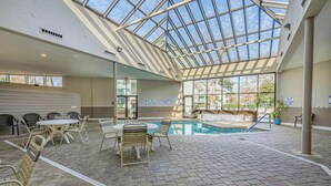 An indoor swimming pool with a glass ceiling, tiled floor, and seating area with tables and chairs. - Updated 2BR MBR Condo. Walk to Beach, Pools, Lazy River & Gated Resort (Myrtle Beach)