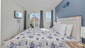 A bedroom with a bed, a TV, a view of the outdoors, and a sign on the wall. - Updated 2BR MBR Condo. Walk to Beach, Pools, Lazy River & Gated Resort (Myrtle Beach)