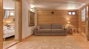 Ein gemütliches Blockhaus-Zimmer mit einer Couch, einem kleinen Tisch mit Lampe und einem Bett.