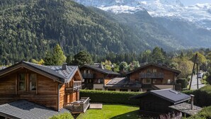 Une rangée de chalets en bois dotés de balcons, se dressant sur un fond de chaîne de montagnes boisée.