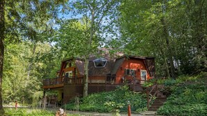 Een chalet met een houten terras, een trap en uitzicht op het omliggende bos.