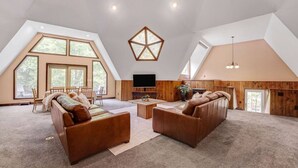 Een ruime woonkamer in loftstijl met hoge plafonds, grote ramen en een gezellige zithoek.