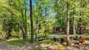 Un terrain de camping équipé d’une table de pique-nique, de chaises et d’un petit étang.