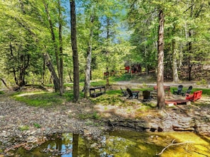 A campsite with a picnic table, chairs, and a small pond.