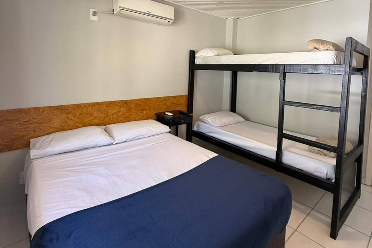 Een slaapkamer met een stapelbed, een nachtkastje en een wandairconditioner.