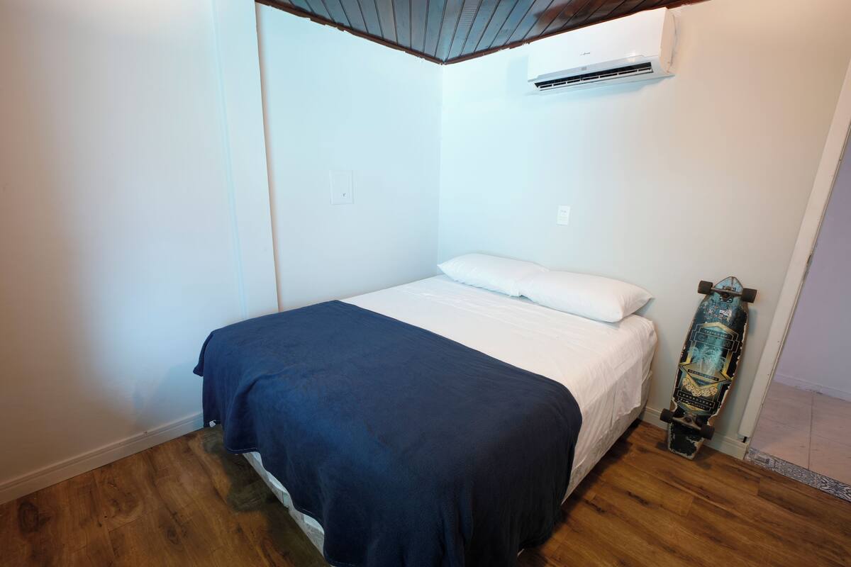 Een slaapkamer met een bed, een skateboard en een airconditioning.