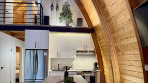 Una cocina moderna con armarios blancos, un refrigerador de acero inoxidable e isla de madera con una bandeja de objetos.