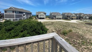 A coastal residential area with multiple two-story houses, some with balconies, and a sandy beach in the foreground.
