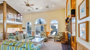 A spacious living room with a high ceiling, a balcony, and large windows. - Borden, Ships Watch Community in Duck, NC (Duck)