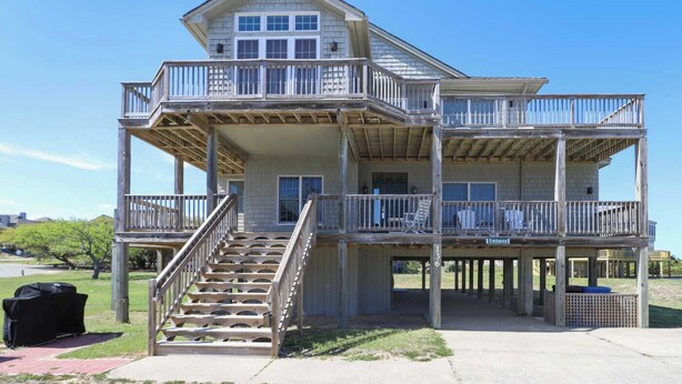 Une maison en bois à deux étages, dotée d ’un balcon à chaque niveau, d’un escalier menant à l’étage supérieur et offrant une vue dégagée sur les environs.
