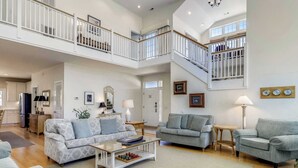Un vaste espace de vie comprenant deux canapés, une table basse et un escalier menant à un niveau supérieur.