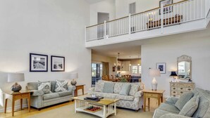 Un salon spacieux avec deux canapés, une table basse et un coin repas visible à travers une porte ouverte.