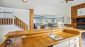 Een ruime keuken met houten aanrecht, een inbouwspoelbak, en een eetgedeelte met een grote tafel en stoelen.