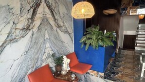 A lobby with a marble wall, a blue accent wall, a wicker lamp, and a potted plant.