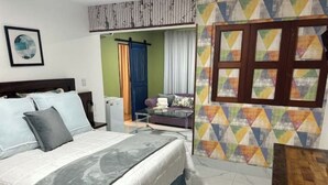 A bedroom with a bed, a desk, and a colorful wall pattern.